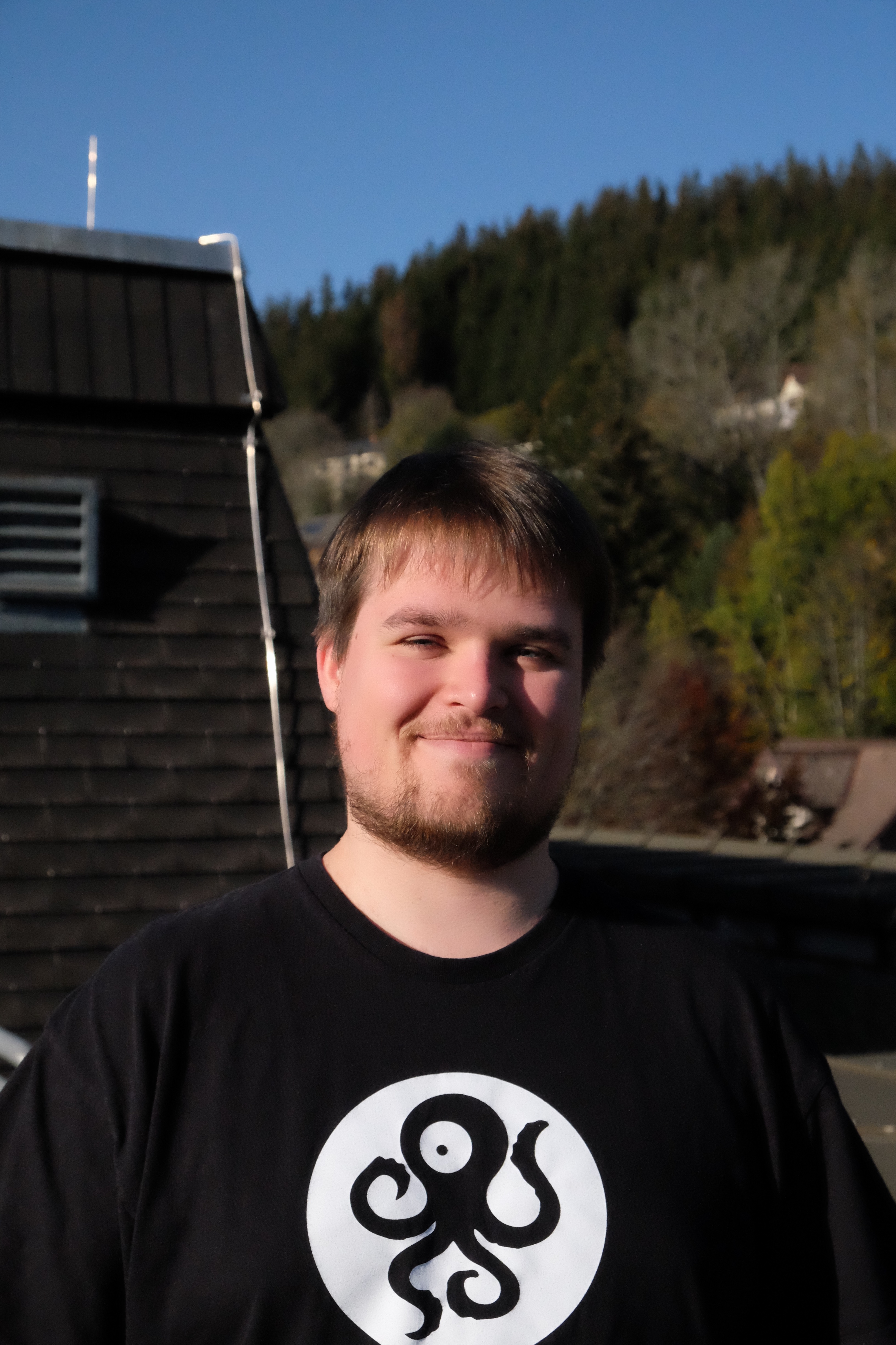 A picture of Florian, brown hair, black shirt, on the roof of the C building.